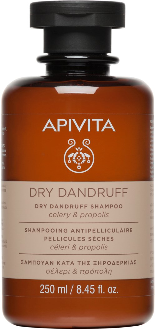 A brown bottle with a black cap containing Apivita Dry Dandruff shampoo for dry scalp. The label has white and beige text.