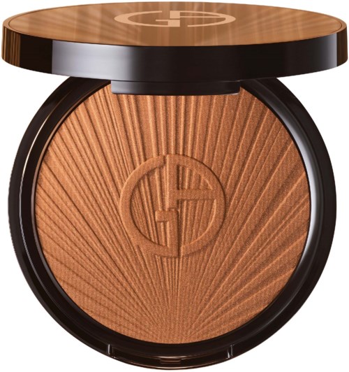 A compact powder with a sunburst pattern and a logo in the center, used for makeup.