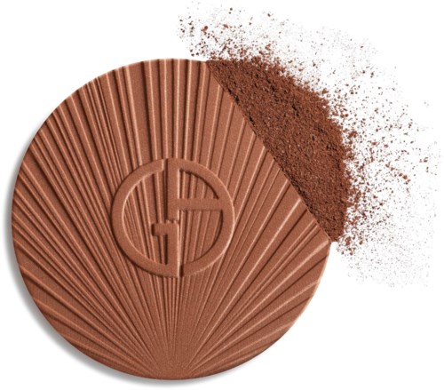 A round makeup blush with a sunburst design and a logo in the center, partially dusted with powder.