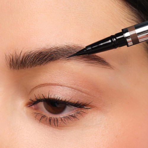 Eyeliner pen applying a dark line along the upper eyelid on a person's eye. Close-up view of eye makeup application.
