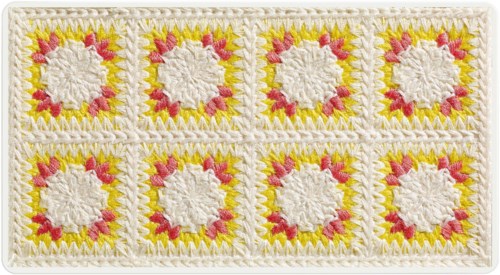 En dekorativ broderad textil med åtta kvadratiska lappar, med vita cirklar i mitten och omgiven av gult och rosa design.