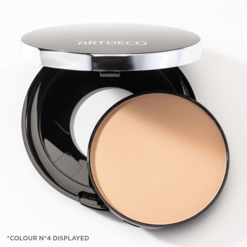 A compact with a mirror open and a beige pressed powder inside. The lid reads 'ARTDECO'.