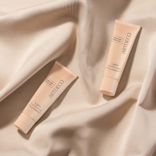 Two tubes of Artdeco Light Luminous Foundation on cream-colored fabric.