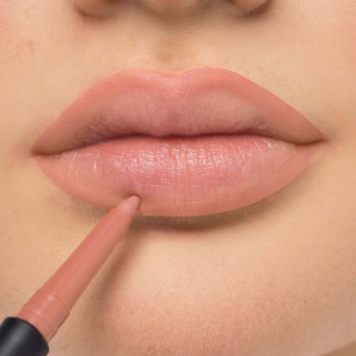 Close-up of lips with a person using a lip liner to define the shape.