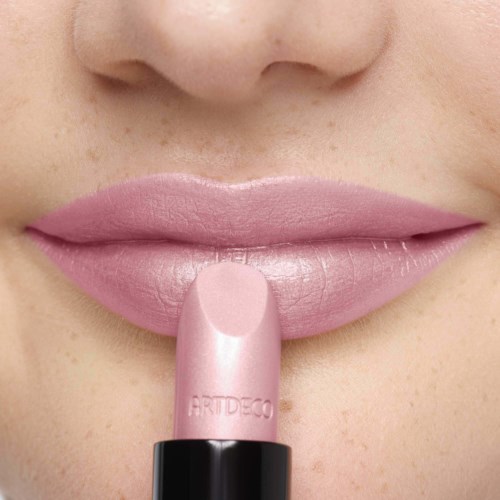 Närbild av läppar med ljus rosa läppstift, finger som rör vid läpparna, slät hud, del av näsa syns.