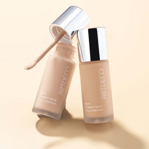Two bottles of foundation, one open with a wand, light beige color, simple design, on a light background.