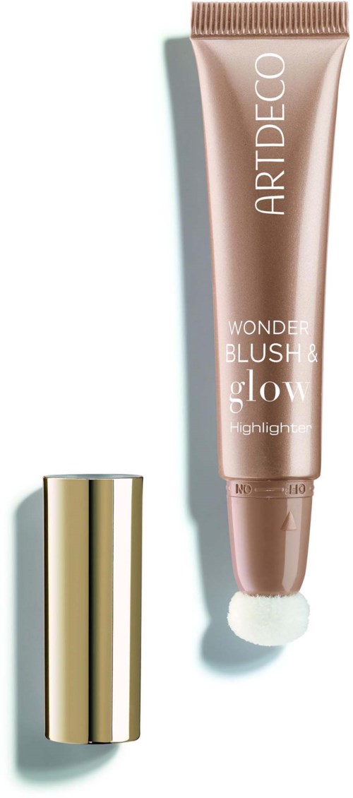 A tube of makeup with a gold cap and a light pink body, labeled Wonder Blush & Glow, with a sponge applicator.