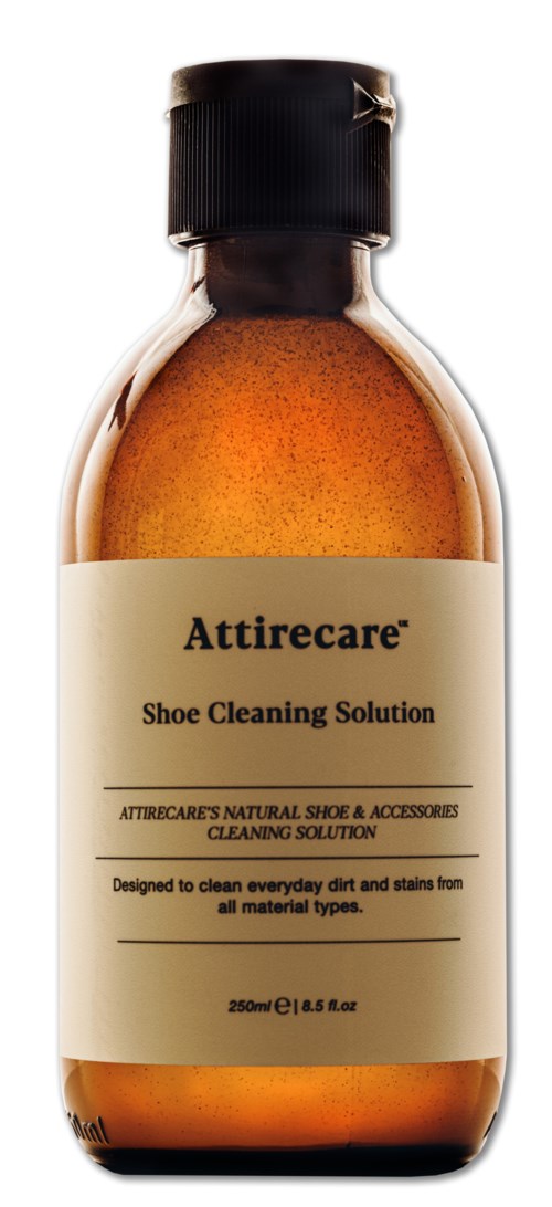 En lille brun flaske med sort skruelåg, mærket 'Attirecare Shoe Cleaning Solution.'