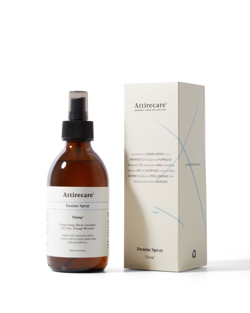 En brun sprayflaske og en hvit eske med blå linjer, merket Attirecare Denim Spray for bukser.