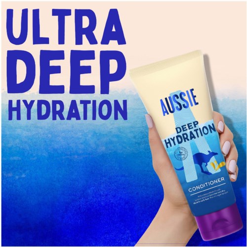 En hånd holder et rør med Aussie deep hydration balsam med blå og gule farver, der fremhæver fugtighed.