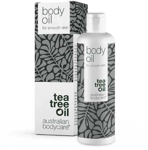 En vit flaska och box med bladmönster, märkt 'body oil' och 'tea tree oil', för skönhetsvård för huden.