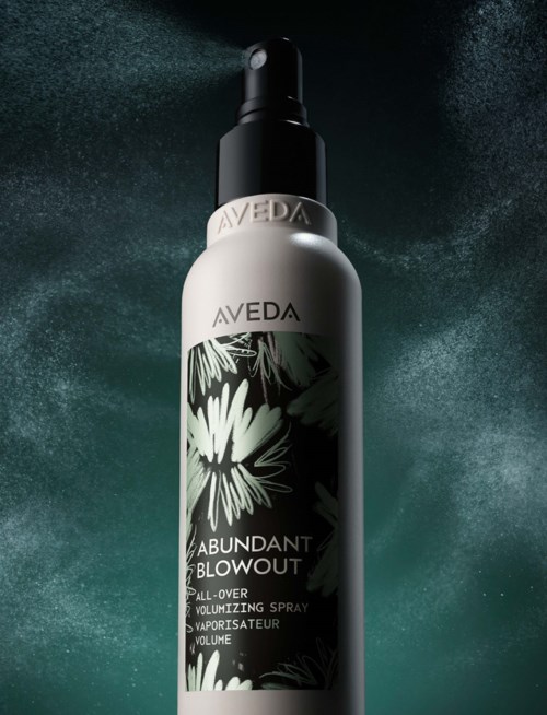 Srebrna butelka sprayu Aveda Abundant Blowout z czarną nakrętką i kwiatowym wzorem etykiety.