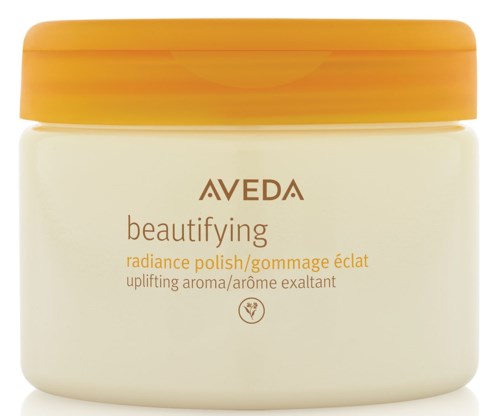En burk av Aveda beautifying radiance polish med lock i gult-oranscht och kropp i vitt.