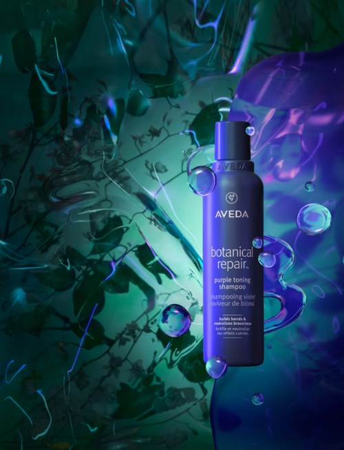 Sininen Aveda botanical repair shampoon pullo ympärillä sinisiä ja violetteja abstraktiasioita ja kuplia.