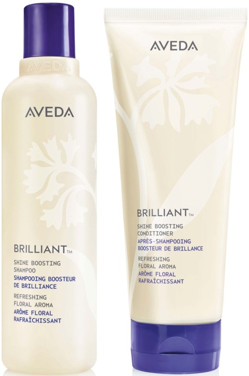 En flaske og en tube af Aveda Brilliant Shine Boosting Shampoo og Conditioner med blomsterdesign på emballagen.