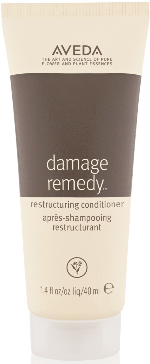 En tube med Aveda Damage Remedy omstrukturerende balsam for hår, i beige og mørk brunt med produktinformasjon.