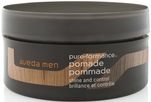 Musta sävyinen purkki, jossa on ruskea ja oranssi suunnittelu, teksti sanoo Aveda Men pure performance pomade, kiiltoa ja hallintaa varten.
