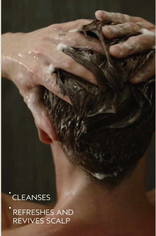 En person vasker hår med shampoo for at rense og opfriske hovedbunden.
