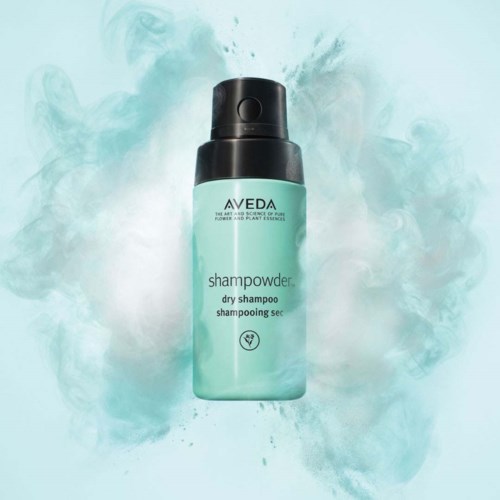 En flaska Aveda torrschampo med svart sprutfots, omgiven av ljusgrön prövning eller spray.