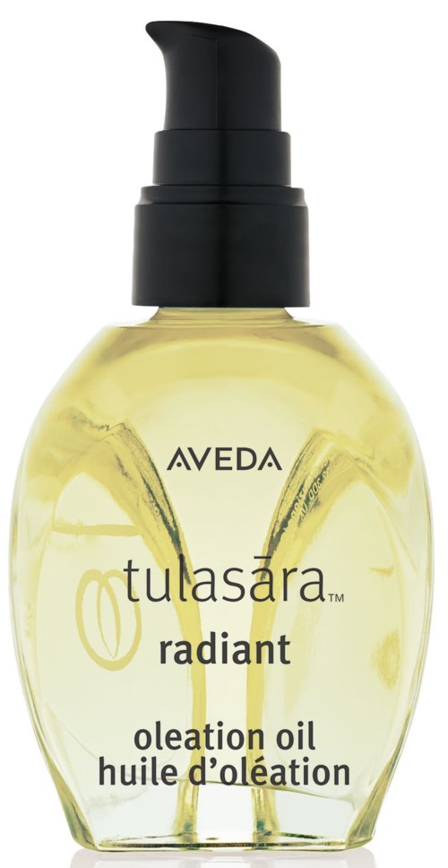 Eine transparente Flasche mit gelbem Öl und Pumpe, beschriftet Aveda Tulasara Radiant Oil für Hautpflege.