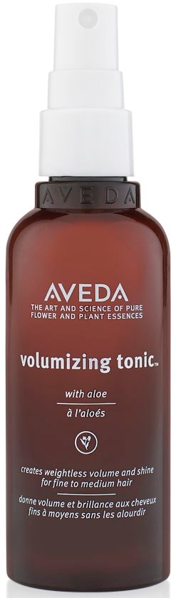 Ruskea suihkepullo valkoisella suuttimella, merkitty Aveda-volumeivapaa hoitoaine aloe veralla.