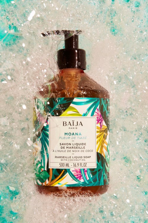 A liquid soap bottle with a tropical leaf design and a black pump, surrounded by bubbles and water.