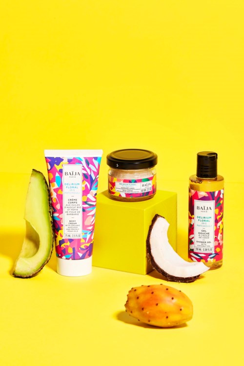 Skincare products with colorful packaging, surrounded by tropical fruits on a yellow background.