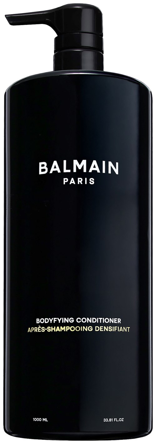 En lång svart flaska med pump, märkt Balmain Paris, för kroppsvård.