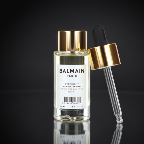 En klar flaska med droppare och svart och guldtoppar för Balmain Paris Overnight Repair Serum.