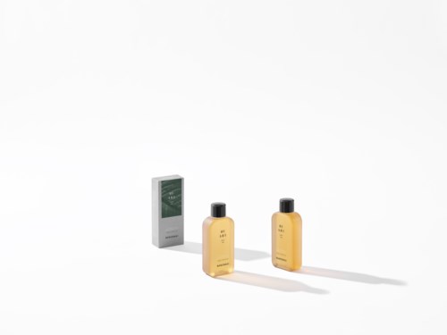 Two yellow bottles of shampoo or body wash and a small box against a plain white background.