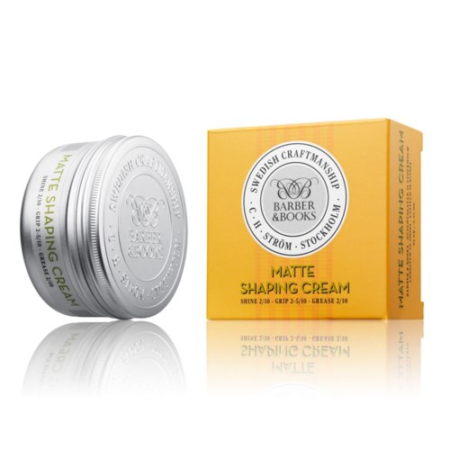 Ett vitt burk och en gul box med hårvårdsprodukter. Burken står det 'Matt Shaping Cream' med produktinformation.
