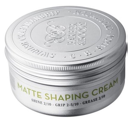 En rund, silverfärgad behållare med etikett 'Matte Shaping Cream' och instruktioner för glans, grepp och fett.