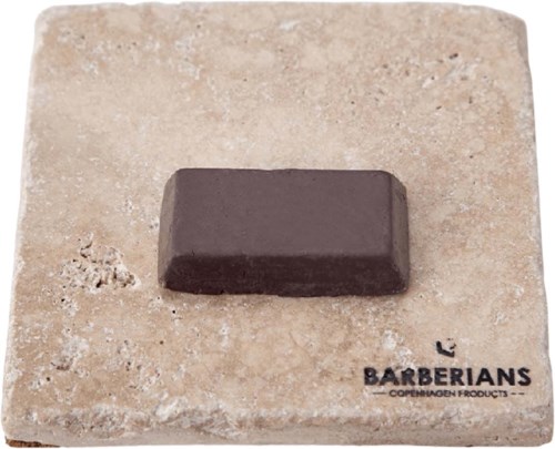 A small, dark chocolate piece on a stone slab with the Barbersians logo and text.