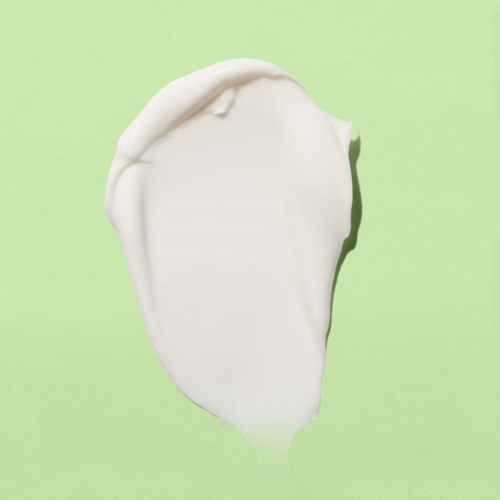 A blob of white cream or lotion on a light green background.