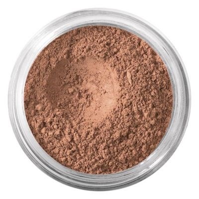En burk med brunt pulver, möjligtvis makeup eller krydda, med en ojämn yta inuti.
