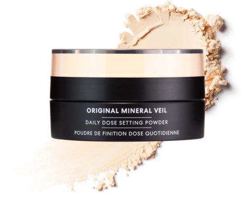 En svart och silver kosmetikask container märkt original mineral veil daglig dos inställningspuder med utspilld puder runt den.