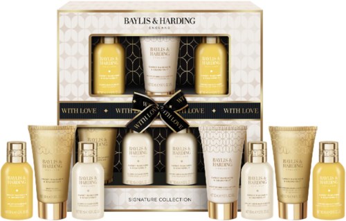 A gift set with yellow and white skincare bottles and tubes, arranged in a box with black ribbon and gold accents.