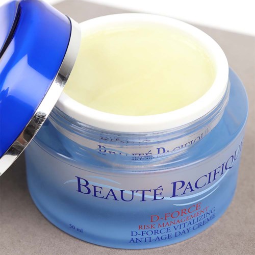 Blauwe pot met Beauté Pacifico D-Force anti-aging dagcrème, gedeeltelijk open, met gele crème.