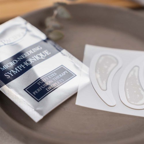 Ett paket märkt 'Micro-Needling Symphonique' och två maskblad på en grå bricka.