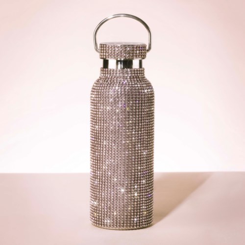 Eine Wasserflasche, bedeckt mit funkelnden Strasssteinen, mit einem silbernen Griff an der Spitze.