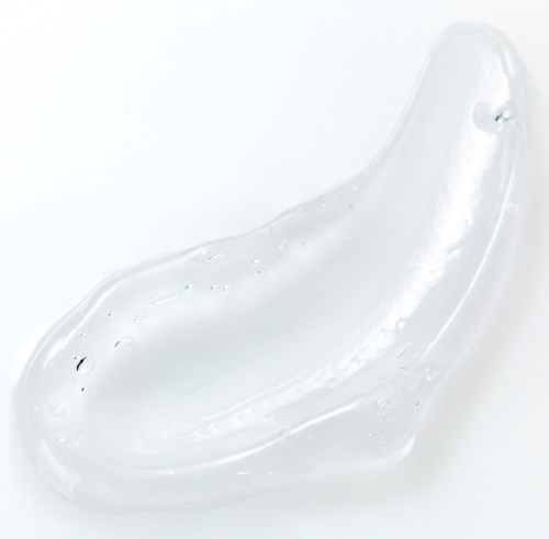 En klar, buet gelé- eller væskeflakse på hvit bakgrunn med glatt, skinnende overflate.