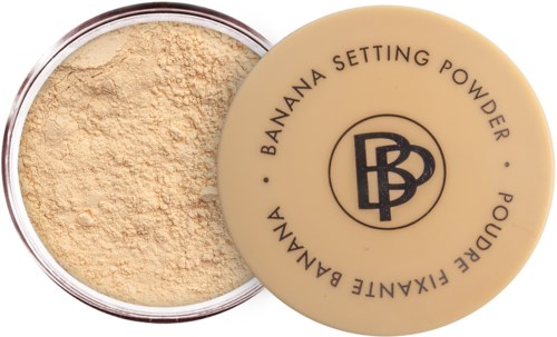 En rund behållare med beige pulver inuti och ett lock med texten 'Banana Setting Powder' och märkeslogga.