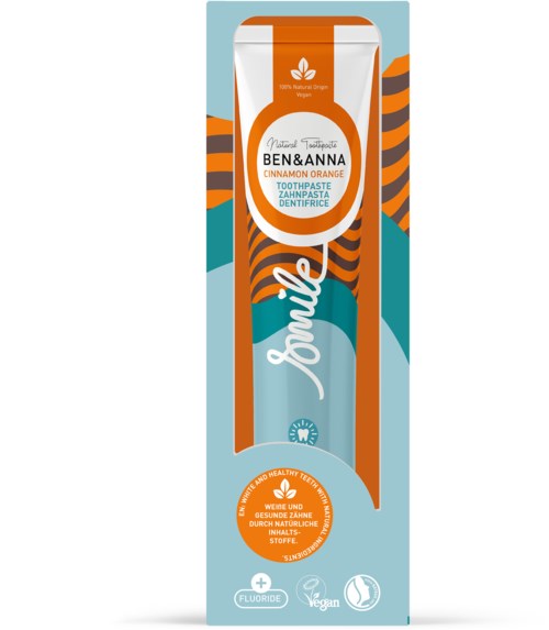 Zahnpasta mit Zimtapfelsinaft und Orangenaroma, natürliche Zutaten, vegan und fluoridefrei, mit buntem gestreiftem Design.