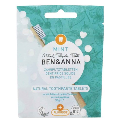 Grønn emballasje med tannbørste og bobler, merket som naturlige tannkremtabletter med fluor og vitamin B12.