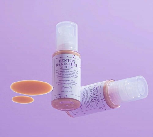 To flasker med Benton Bakuchiol Serum ligger på en lilla overflate, med litt serum ved siden av.