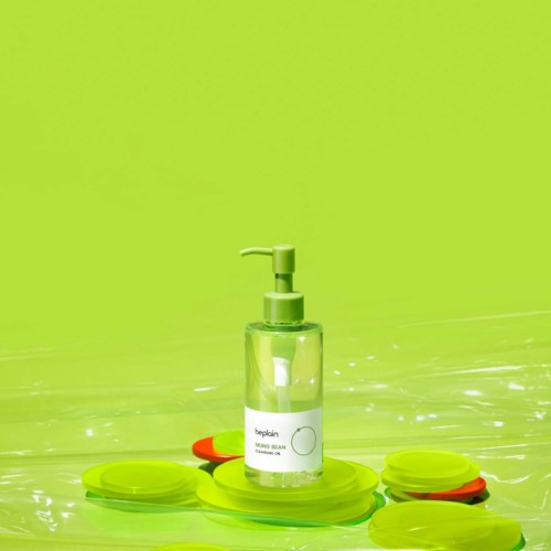Hand sanitizer bottle on a water surface with green and orange floating objects, background is bright green.