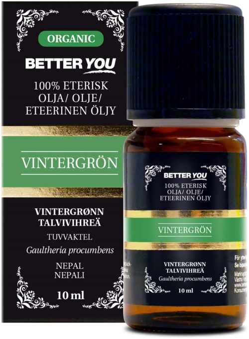 A small brown bottle with a black cap next to a black, green, and white box. Labels show wintergreen oil from Nepal.