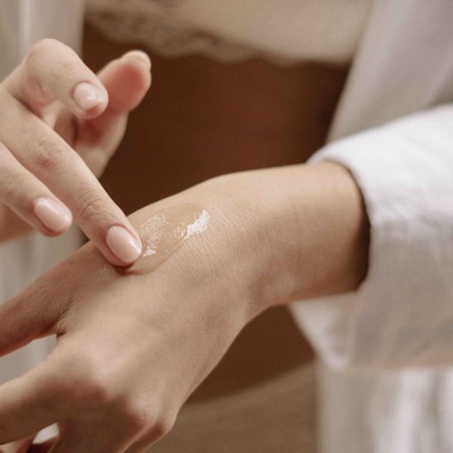 En person som påfører lotion eller krem på hånden med en annen persons finger.