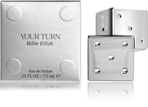 A perfume box and three silver dice, with some reflections on a white surface.