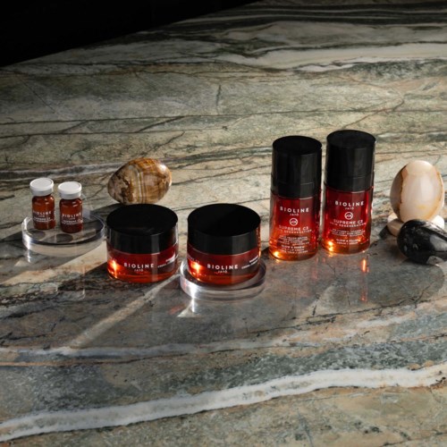 Beauty products and shells on a marble surface with natural lighting.